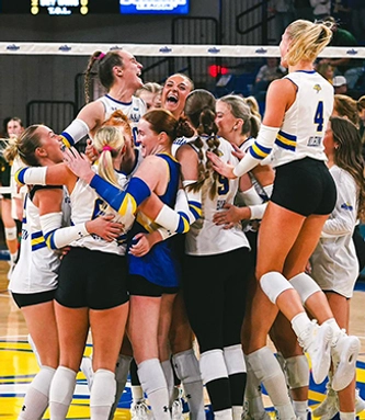 SDSU volleyball team celebrates together in a huddle.