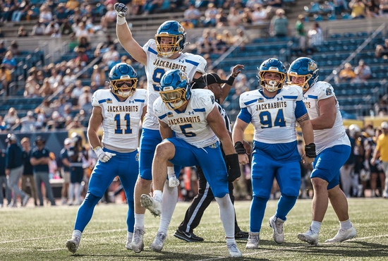 SDSU football team celebrate together on the field.