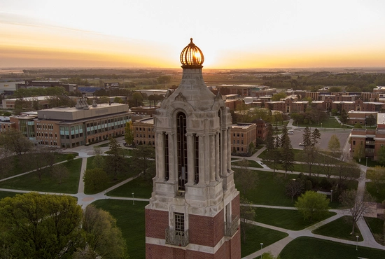 Aerial photo of the Coughlin Campanile with the SDSU campus in the background during a sunrise.