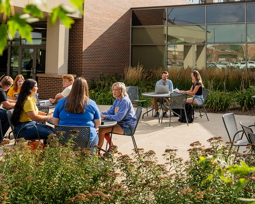 SDSU students sitting at outdoor tables outside of the Student Union.