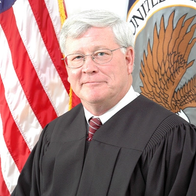 Alan Lance in his judge attire smiles at the camera