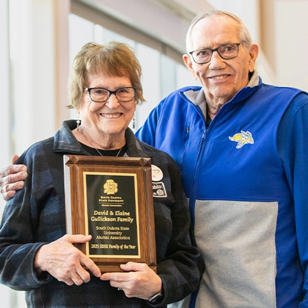 Elaine and Dave Gullickon smile holding the "family of the year" plaque