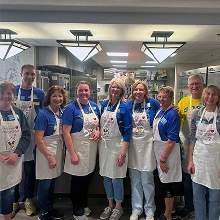 Large group of people wearing white aprons after volunteering at a Ronald McDonalds House.