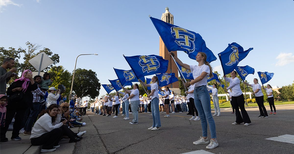 The SDSU flag team performs during the Yellow & Blue Block Party with the Campanile in the background.