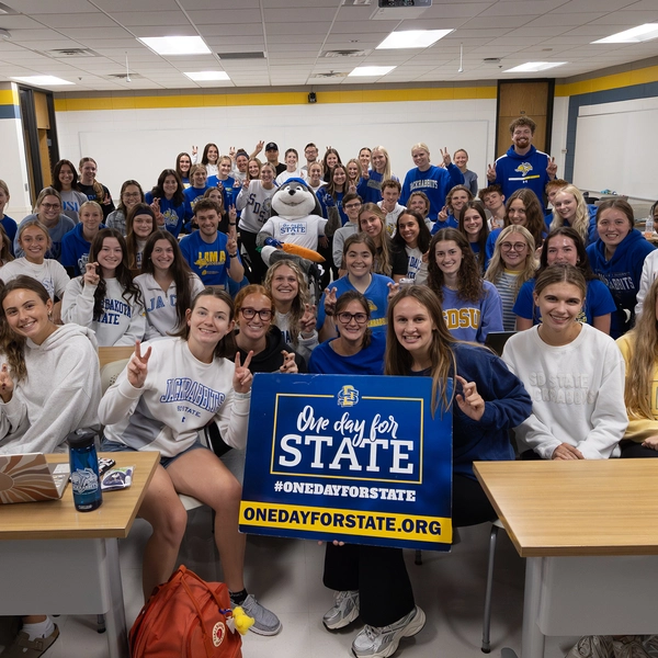 Jack smiles with a lot of college students during a Jacks Journey visit