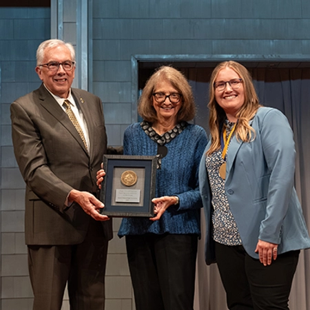 President Dunn holds a plaque with a medallion while standing with a newly endowed holder and the donor who started the endowment.