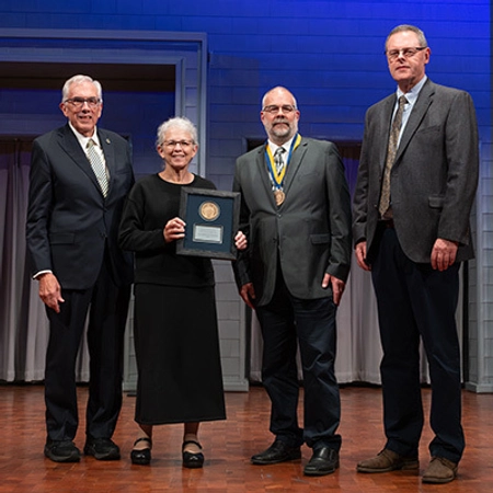 President Dunn is standing with a newly endowed holder and the donor who started the endowment, who holds a plaque with a medallion.