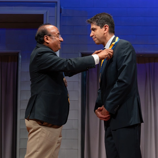 College dean places a medallion around the neck of a newly endowed holder.