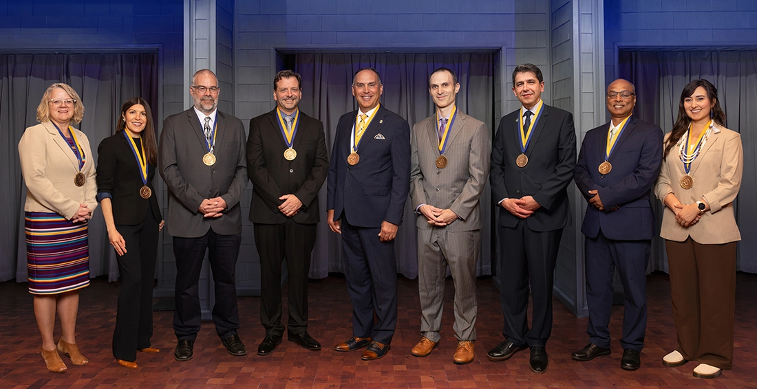 The nine newest endowment holders at SDSU stand side by side on stage smiling, wearing their medallions.