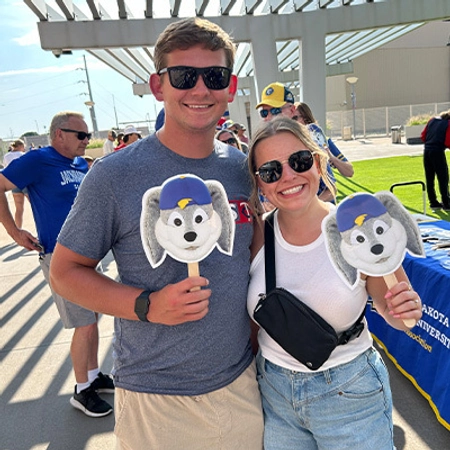 A couple outside holding up signs of Jack the Jackrabbit.