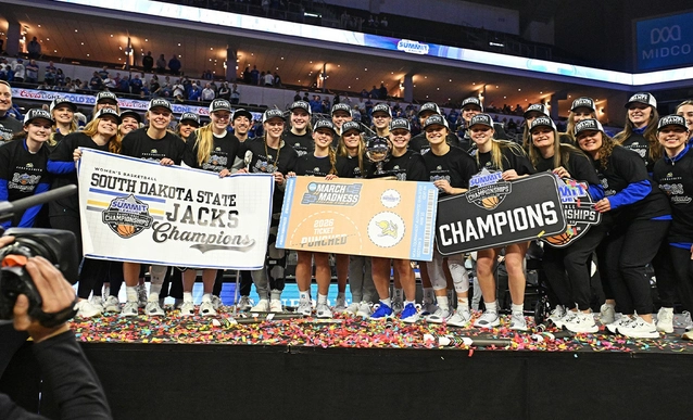 The SDSU women's basketball team celebrates winning the 2026 Summit League Basketball Tournament, holding banners that read "Champions."