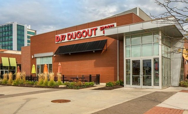 Modern restaurant exterior titled "DJ's Dugout Sports" with wood paneling, glass entrance, and outdoor umbrellas.