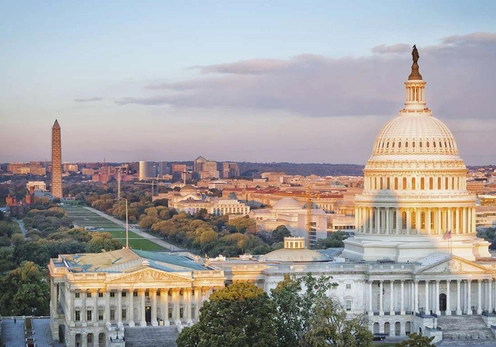 A photo of the U.S. Capitol building with the Washington Monument in the background under a partly cloudy sky.