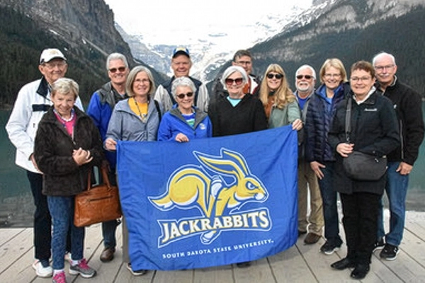 A large group of Jackrabbits traveling together pose for a group photo with the Rockies in the background.