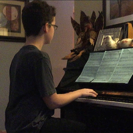 A young Charles Kriech sits at a piano