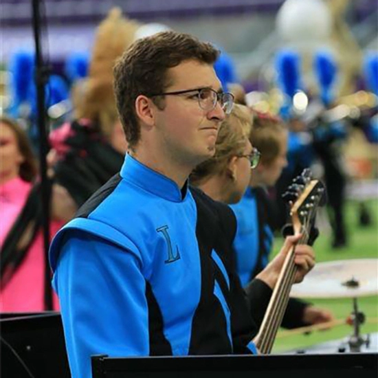 Charles Kriech plays guitar with a marching band on a field