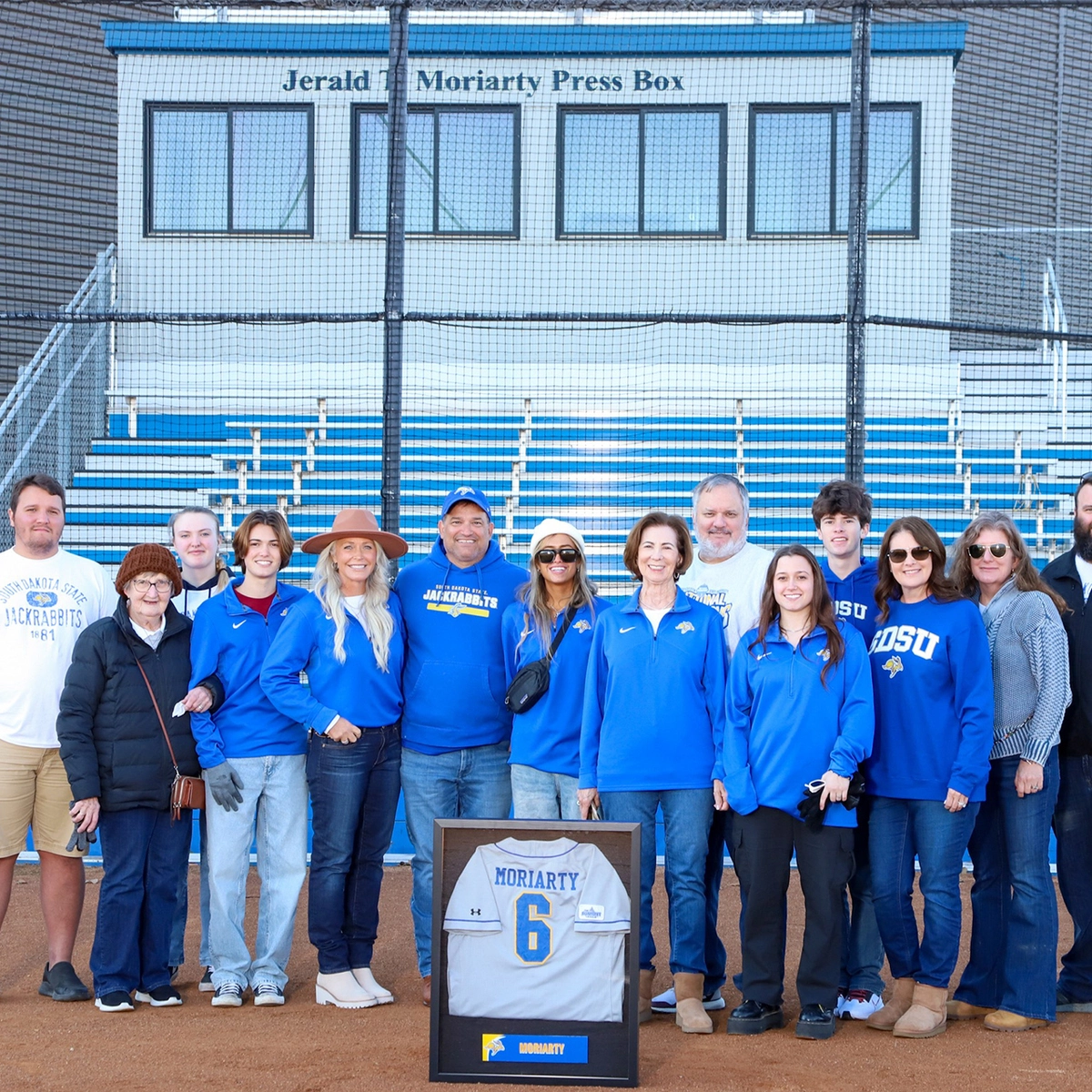 Kevin Moriarty and family stand behind home base with the Jerald Moriarty Press Box in the background