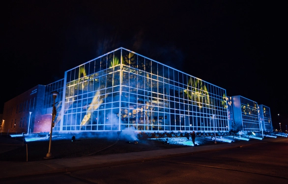 Outdoor photo of Raven Precision Agriculture Center lit up with blue and yellow lights