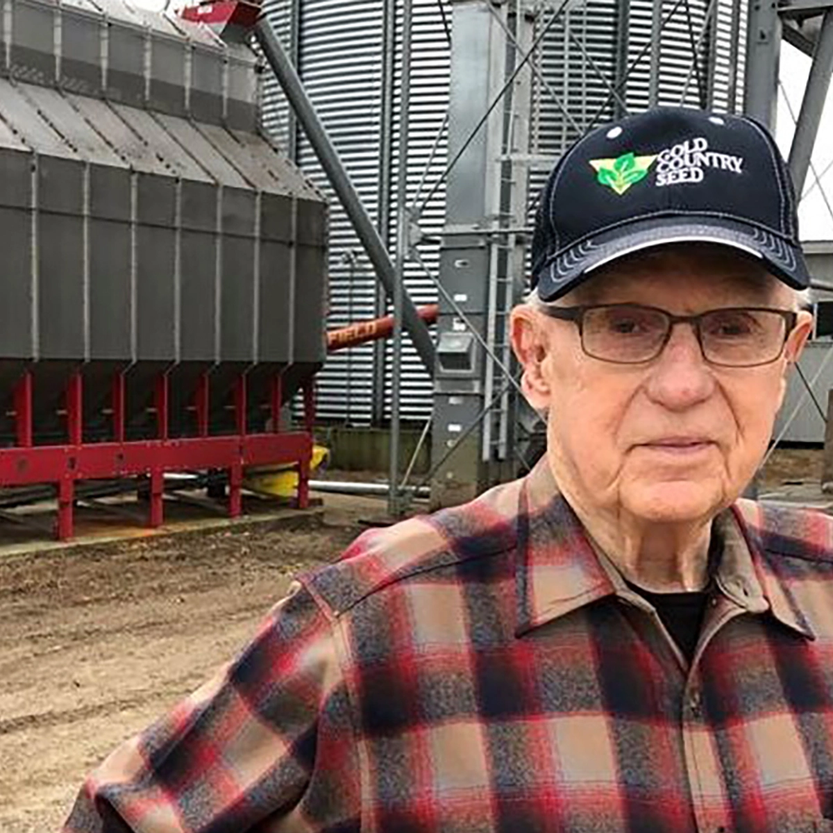 Roger Heller looks at the camera with his farm in the background