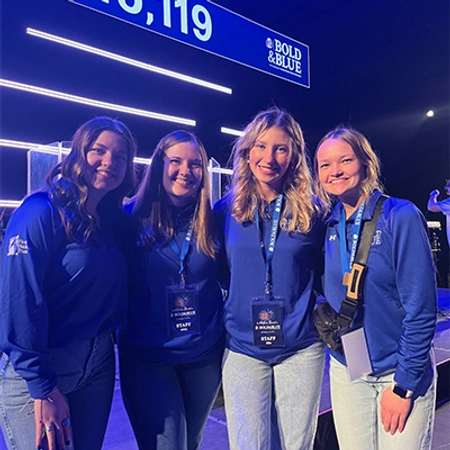 Abby Bruns stands smiling with three other female Jackrabbits Philanthropy Center co-workers