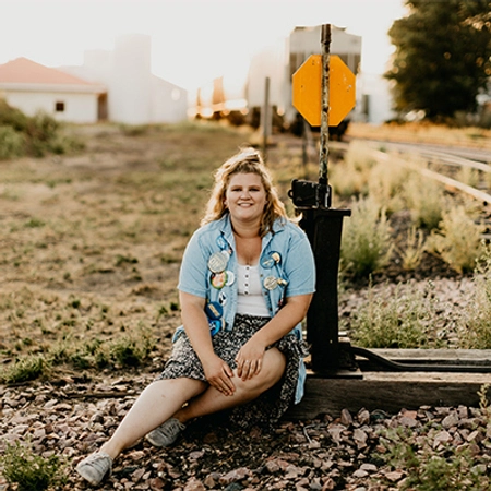 andrea berends in her hobo gear, sitting along a railroad track