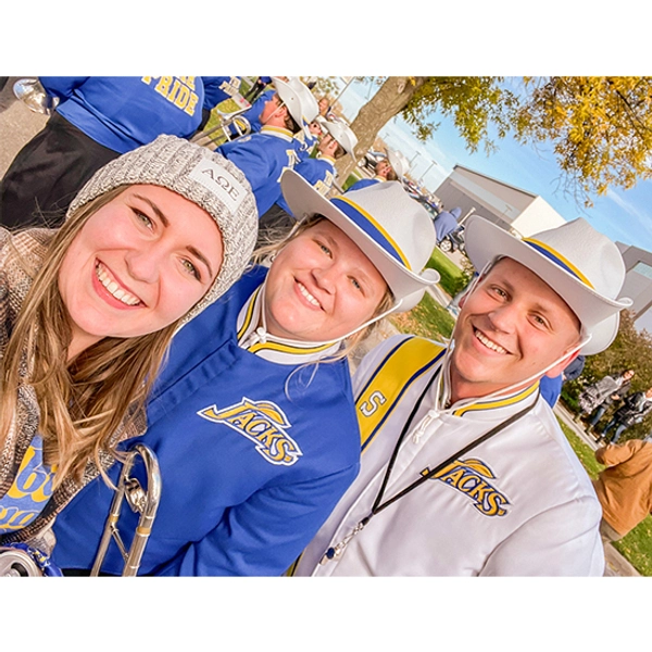 Andrea Berends in her Pride of the Dakotas uniform smiling with two friends