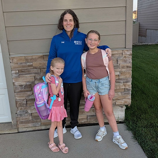 Brandi Haraldson smiles standing in between her two daughters