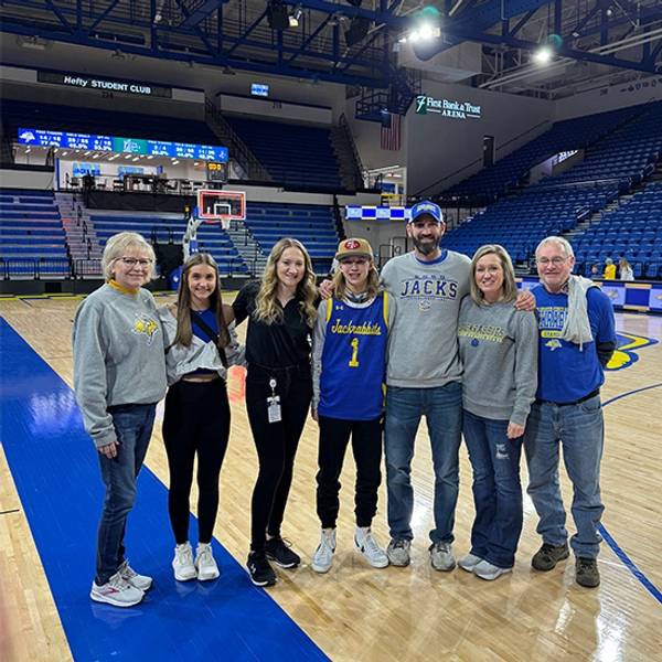 cadence koenig and her family dressed in jackrabbit gear on the basektball court