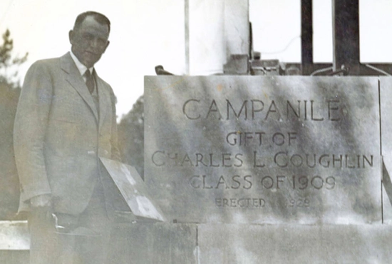 Black and white photo, taken in 1928, of Charles Coughlin with the Campanile cornerstone.