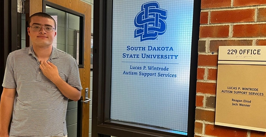 Lucas Wintrode standing in front of the Lucas P. Wintrode Autism Support Services Office.