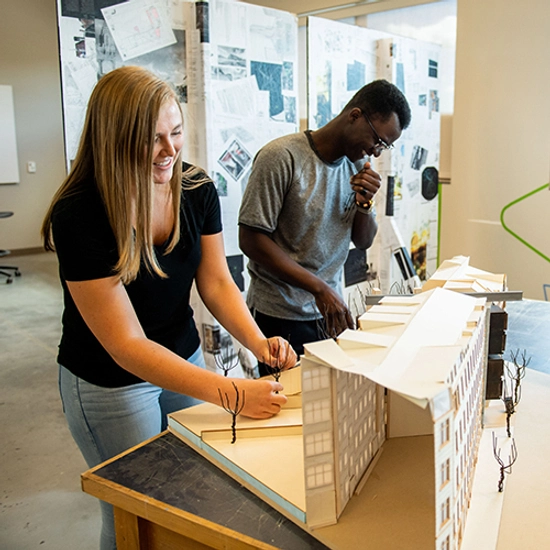 Two architecture students work together on an building model.