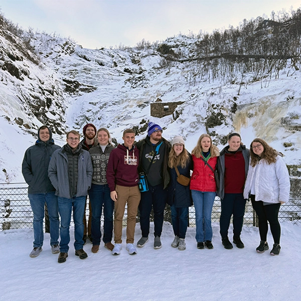 The Choir posing for a picture in front of a snowy valley in Sweden