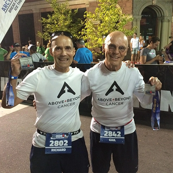 Dick Deming and another male hold up medals after a running competition.