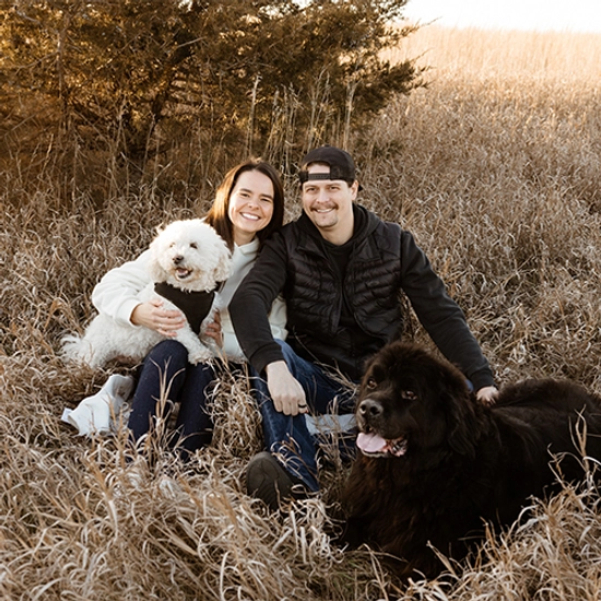 Emily Punt smiles with her husband and two dogs in a field