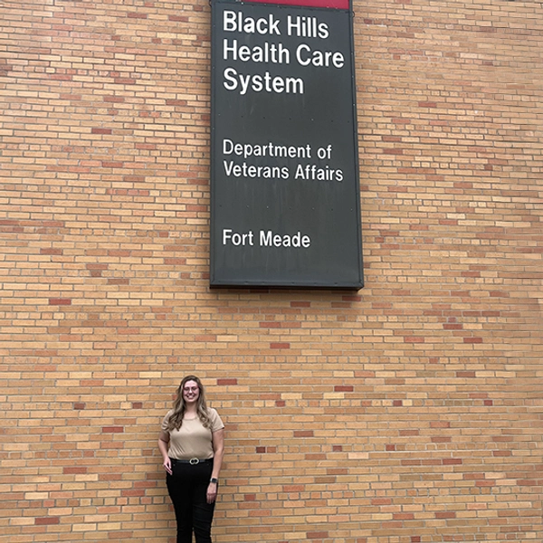 Emily stands infront of the Black Hills Health Care System building and sign.