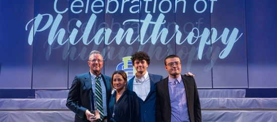 Wintrode family stands on stage holding their Philanthropic Family of the Year crystal award.