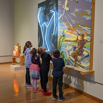 Group of children looking at a painting in an exhibit in the South Dakota Art Museum