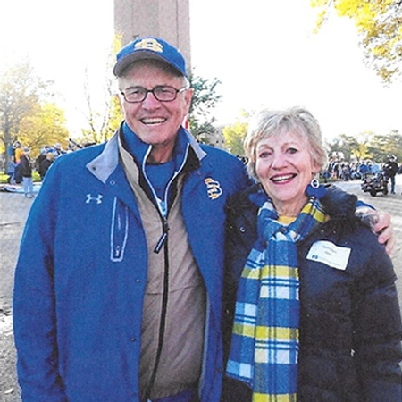 The Gees stand together, dressed in yellow and blue clothing, with the Campanile in the background