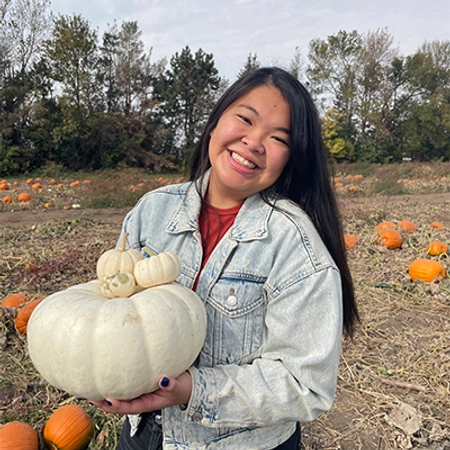 Hailey Gruber smiles holding a pumpkin