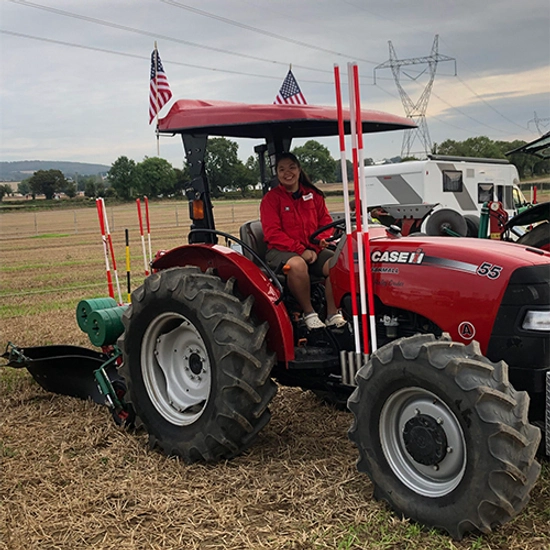 Hailey Gruber sitting in a tractor smiling during a competitive ploughing competition.