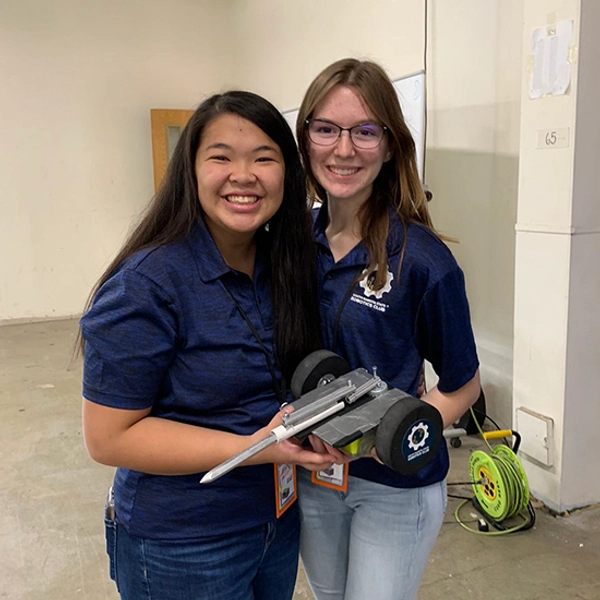 Hailey Gruber smiles with a friend, holding a robot.