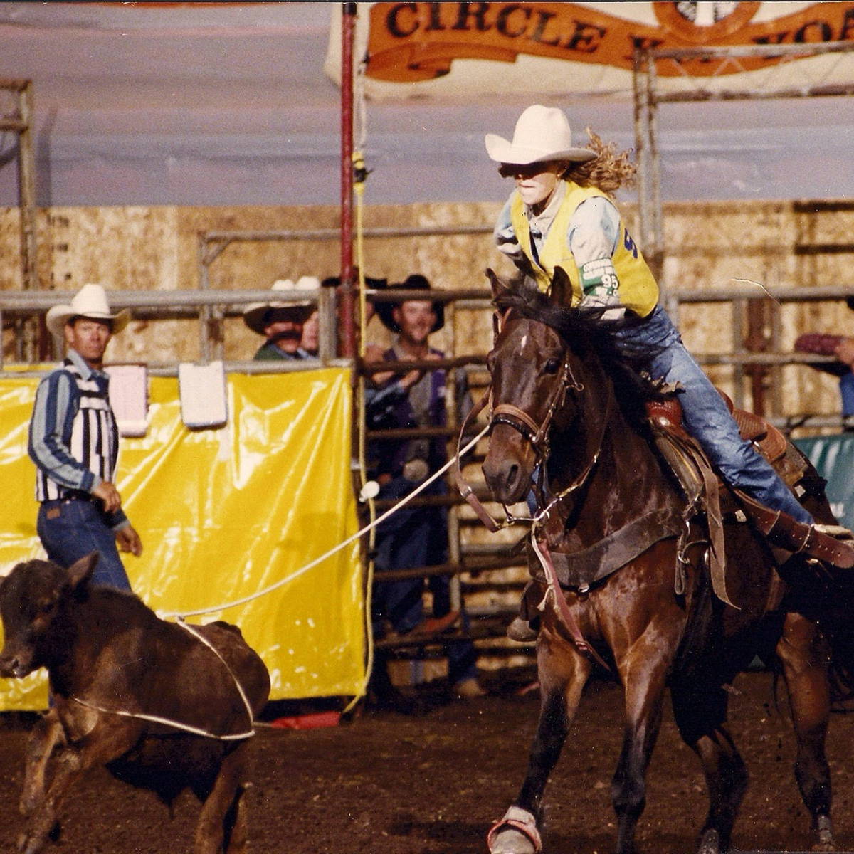 Photo of SDSU rodeo female team member riding a horse and roping a calf.