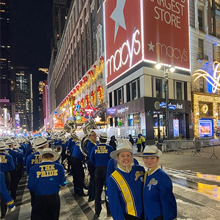 two girls posed in front of the pride band during the Macy's thanksgiving parade