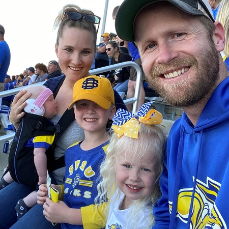 Jenna and her husband and three children in jackrabbit gear at a SDSU football game