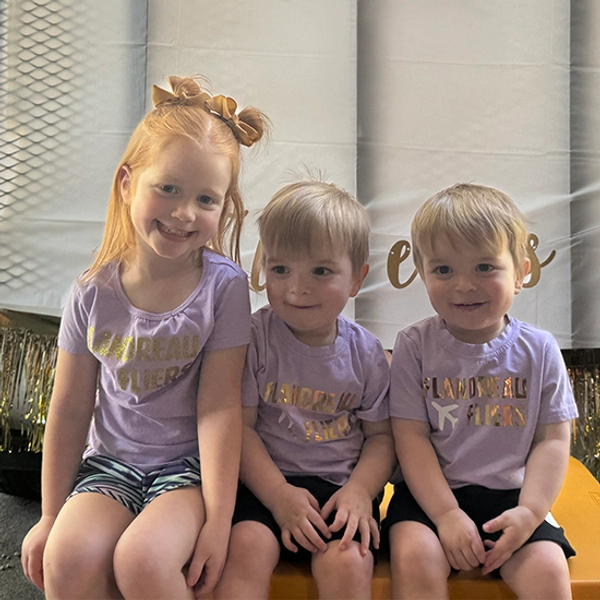 Jillian Baldini's three children lines up smiling for the picture while wearing Flandreau Fliers shirts