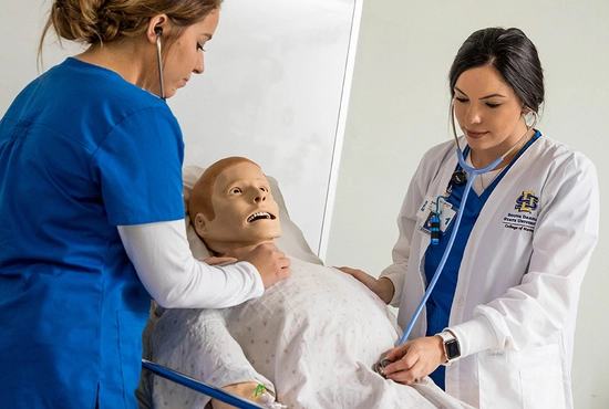 Two SDSU nursing students work together to take care of a mannequin patient.