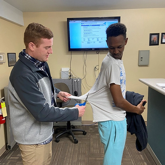 SDSU Student Patrick Niyonshuti during his shirt tail cutting ceremony as another person cuts the back of his t-shirt