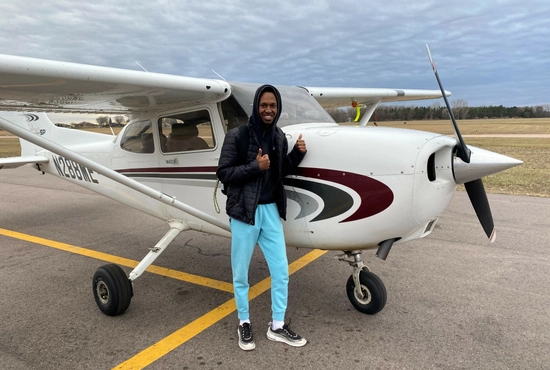 SDSU Student Patrick Niyonshuti standing with thumbs up right by a small aircraft