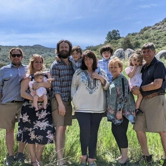 family standing in front of a fence with a pretty landscape in the background