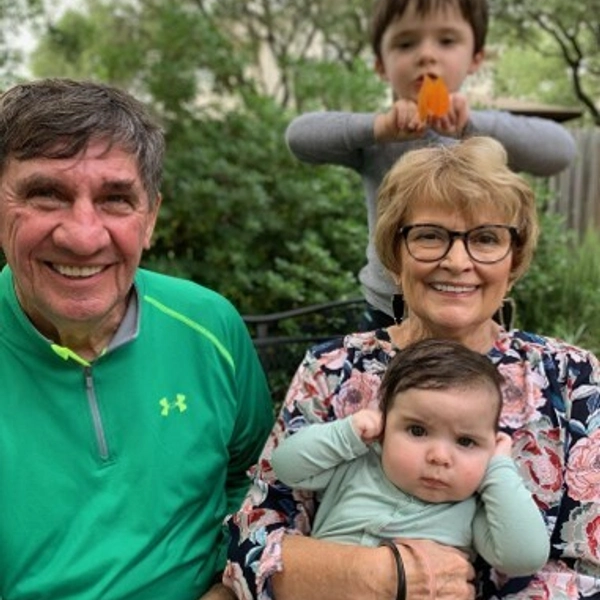 two grandparents holding their two grandchildren, smiling proudly